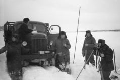 Черно-белая фотография с группой людей в снежное время возле грузовика